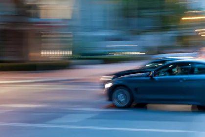 Ein Auto fährt mit hoher Geschwindigkeit durch eine Stadtstraße bei Nacht, verschwommene Bewegung
